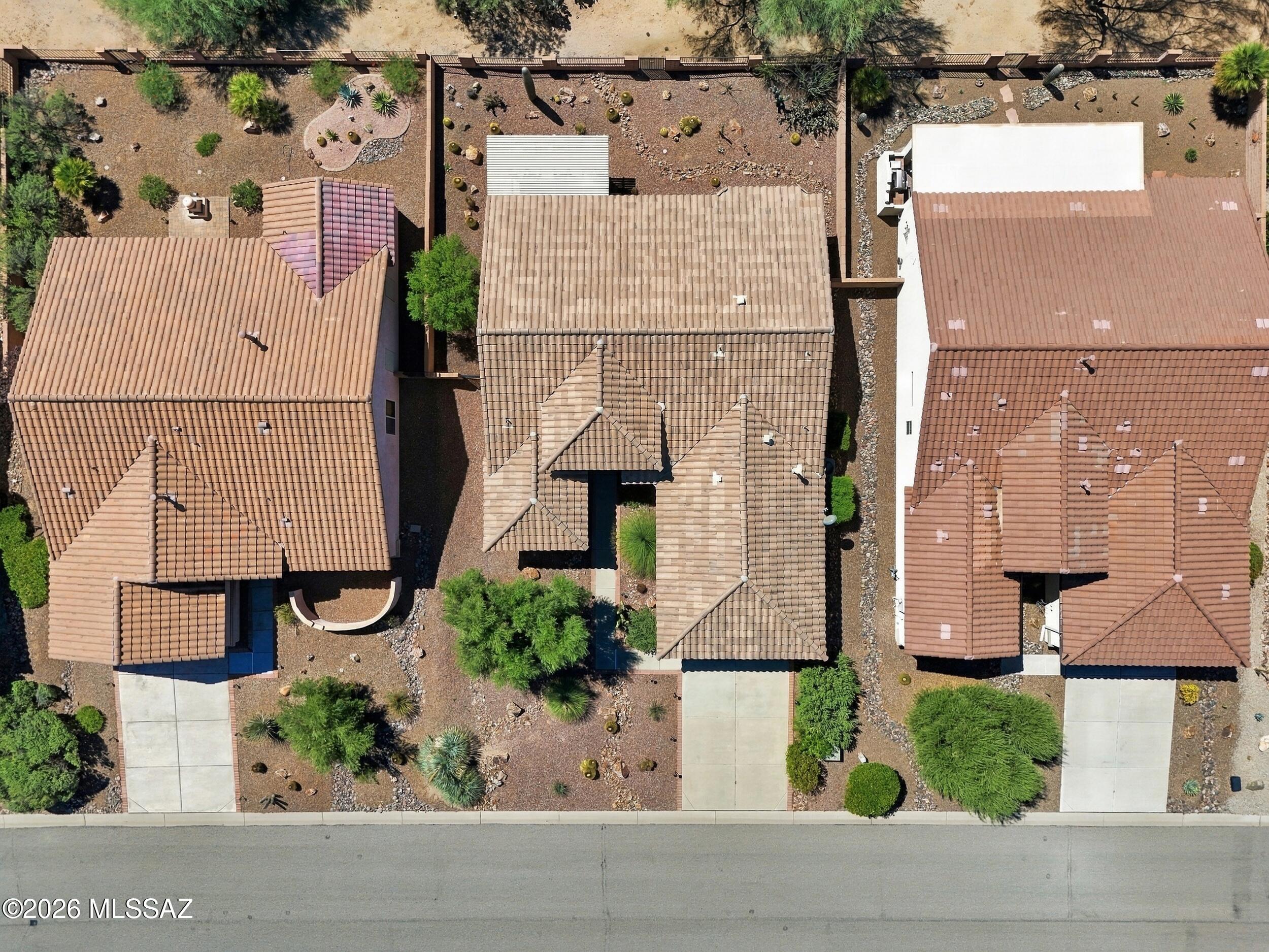 Aerial view of a tan tile-roofed home with desert landscaping between neighboring houses.
