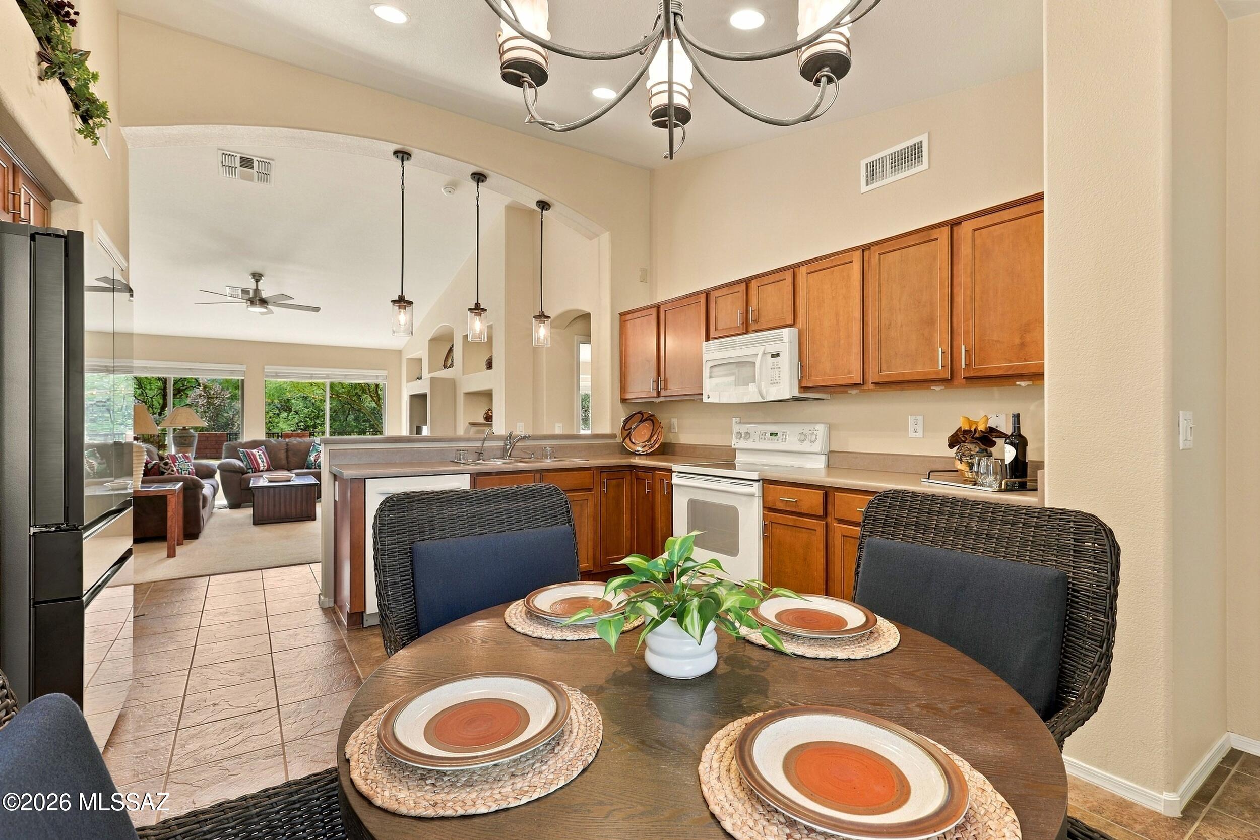 Open-plan kitchen with warm wood cabinets and a set dining table overlooking the living room.