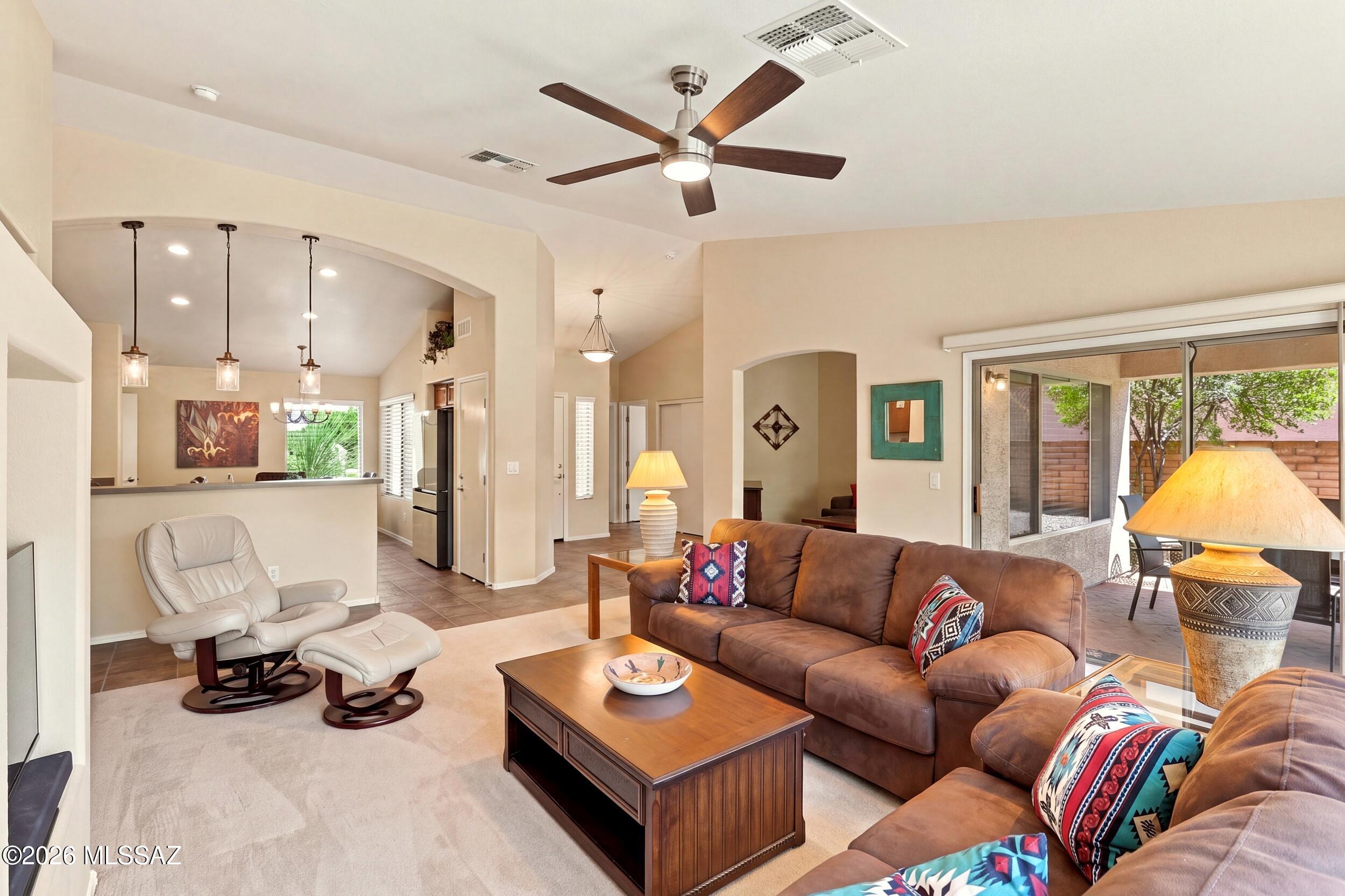 Furnished living room with leather sofas, a white recliner, and sliding doors to a patio.