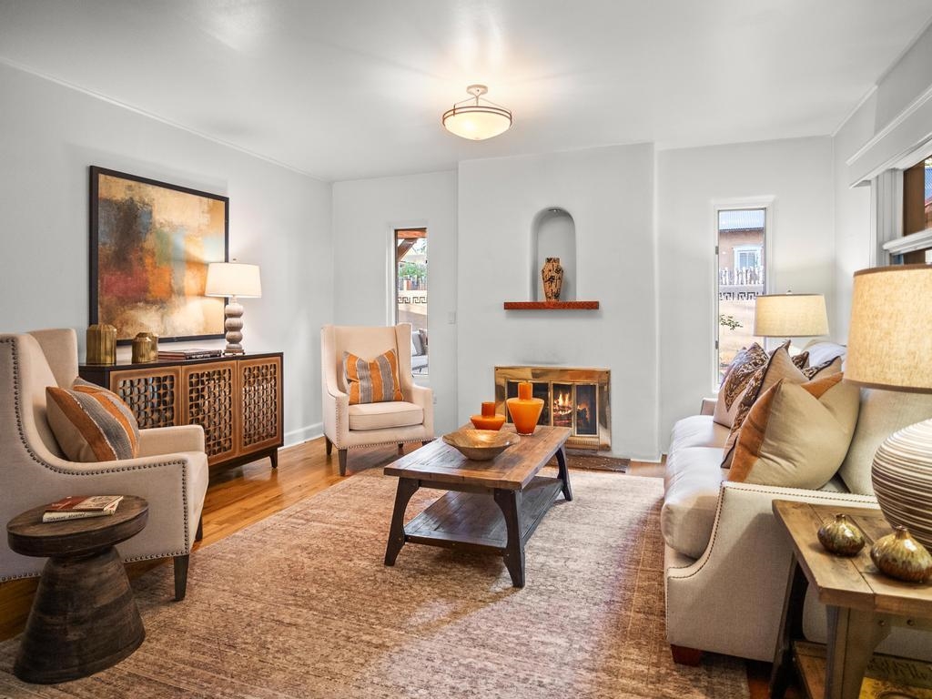 Living room with a fireplace, cream seating, and a wood coffee table on a patterned rug.