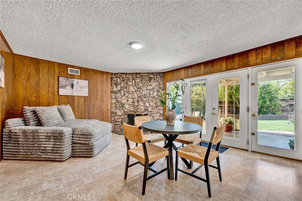 Living and dining area with wood paneling, stone accent wall, and doors to the backyard.