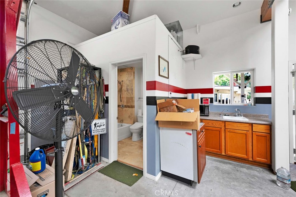 Garage utility area with a large fan, kitchenette, and adjoining bathroom.