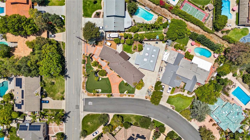 Aerial view of a large home with landscaped grounds, nearby pools, and tennis courts.