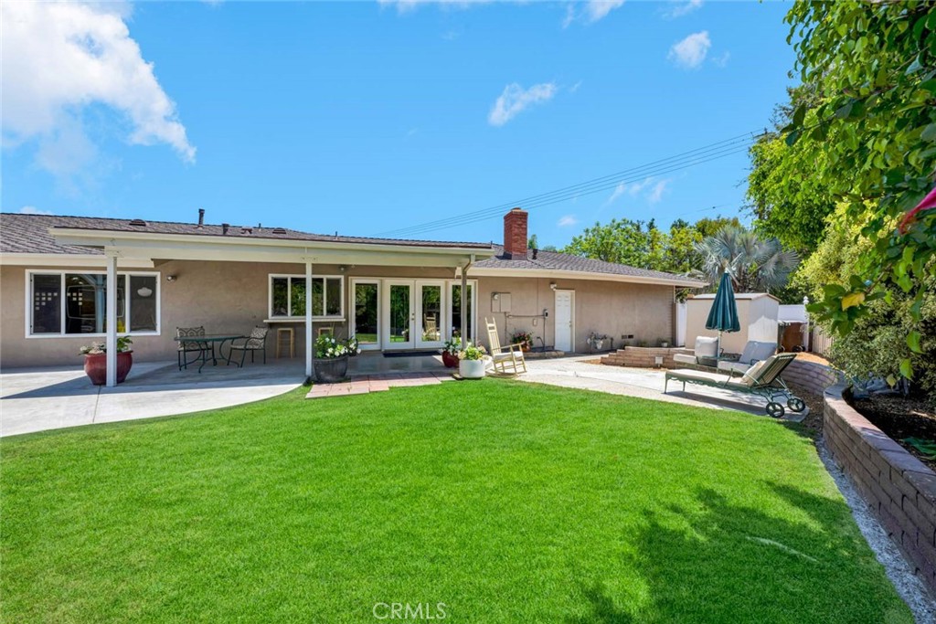 Single-story home with a covered patio, broad lawn, and outdoor lounge area.