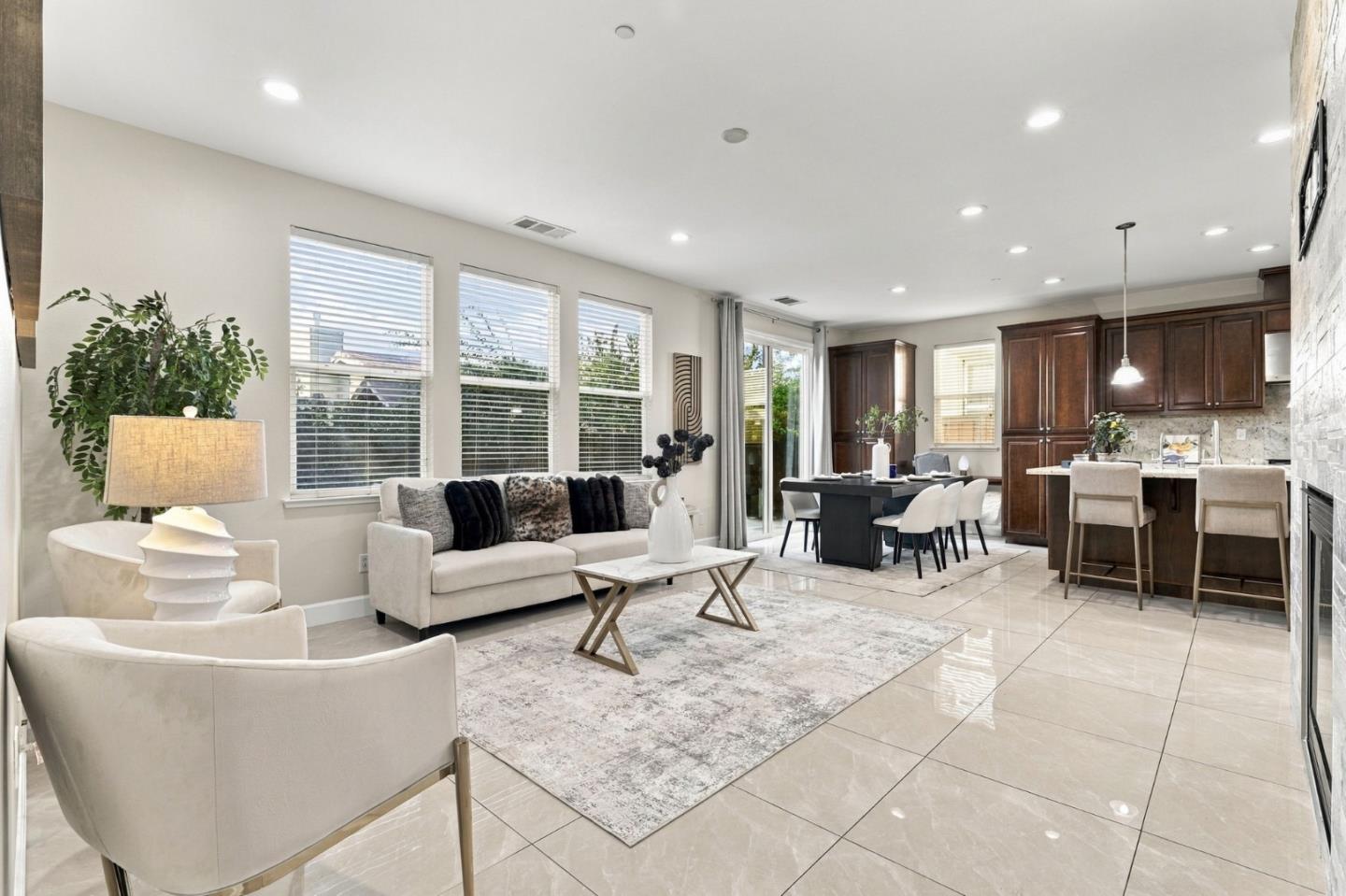 Open-plan living room with pale seating and a dining area beside a dark wood kitchen.