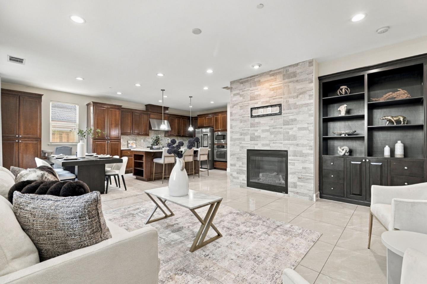 Open-plan living room and kitchen with a stone fireplace and dark wood built-in shelving.