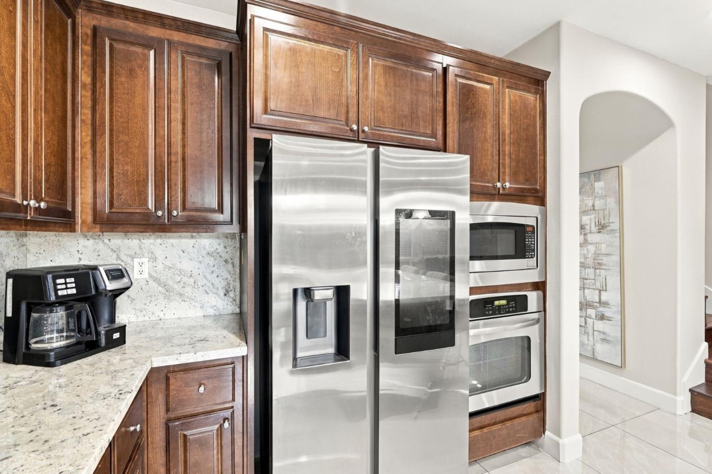 Kitchen with dark wood cabinets, stone counters, and stainless-steel appliances.