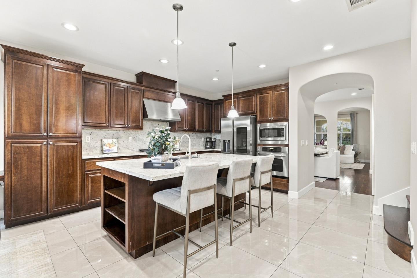 Kitchen with a large stone island, dark wood cabinets, and stainless steel appliances.