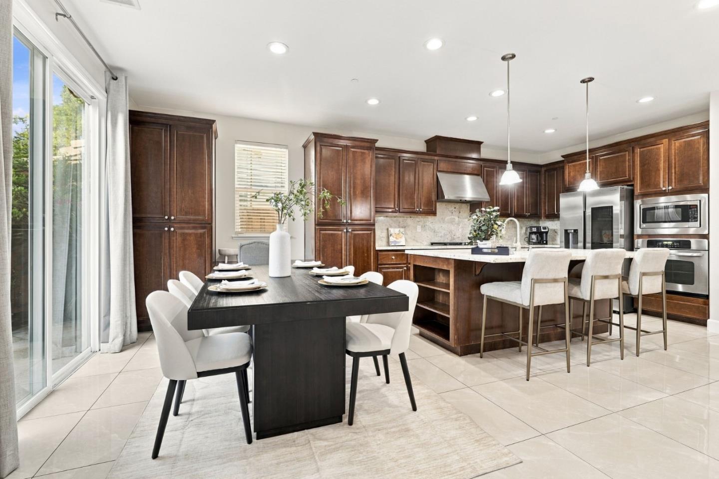 Kitchen and dining area with dark wood cabinets, stainless steel appliances, and a stone-topped island.