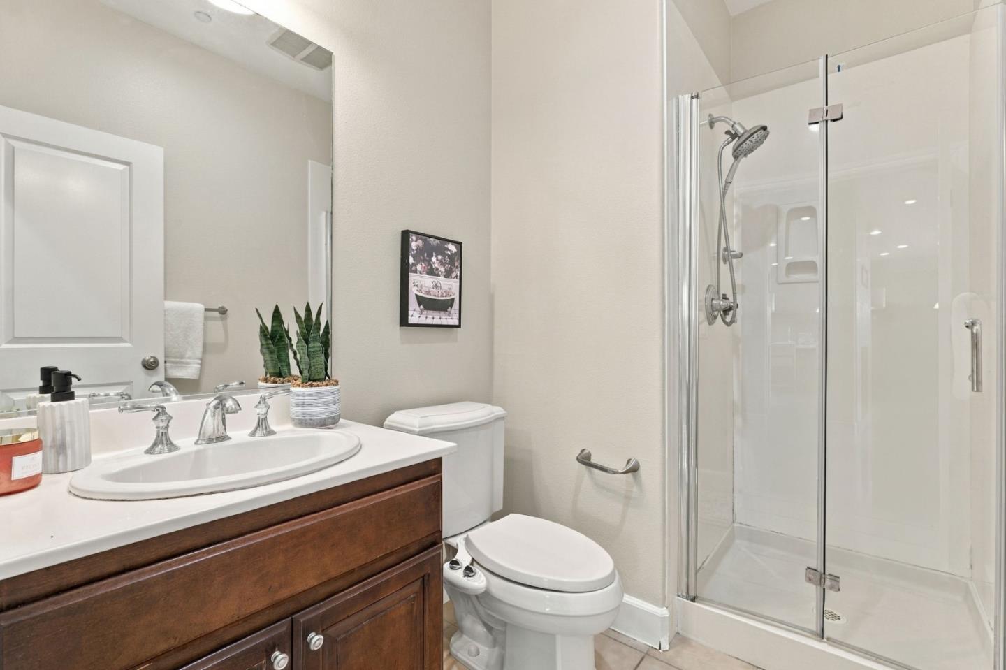 Bathroom with a dark wood vanity, white sink, toilet, and glass-enclosed shower.