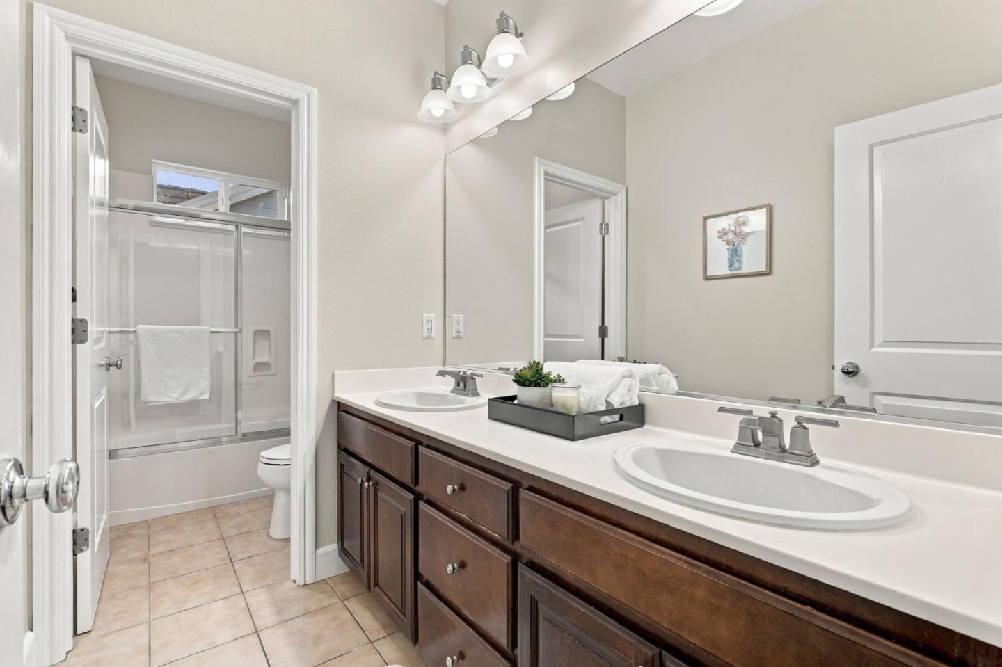 Bathroom with a double-sink vanity and dark wood cabinets beside a glass-enclosed shower.
