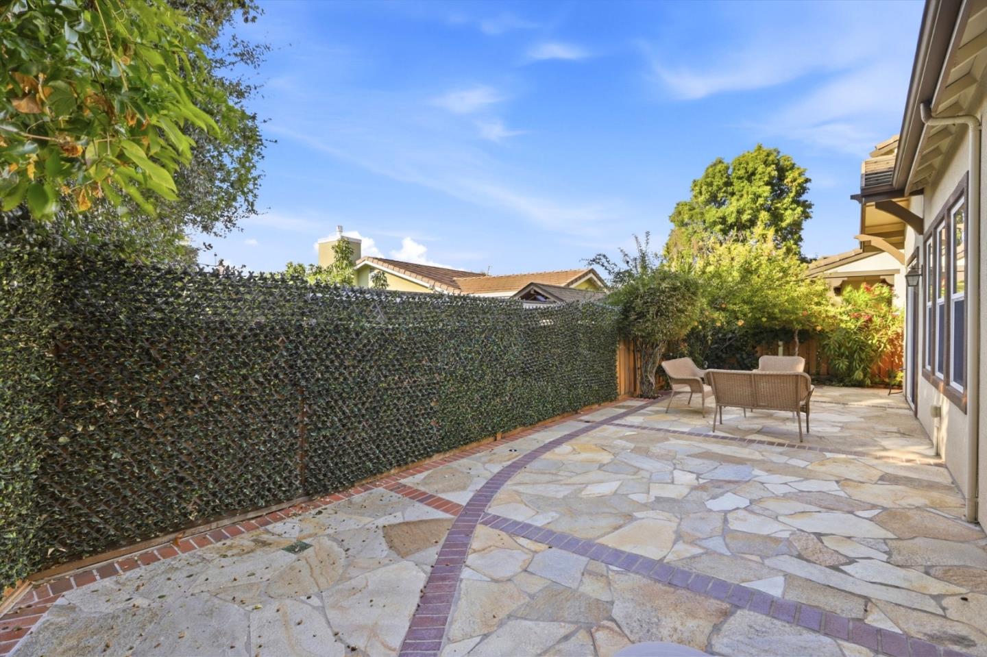 Stone-paved backyard patio with wicker seating beside the house.