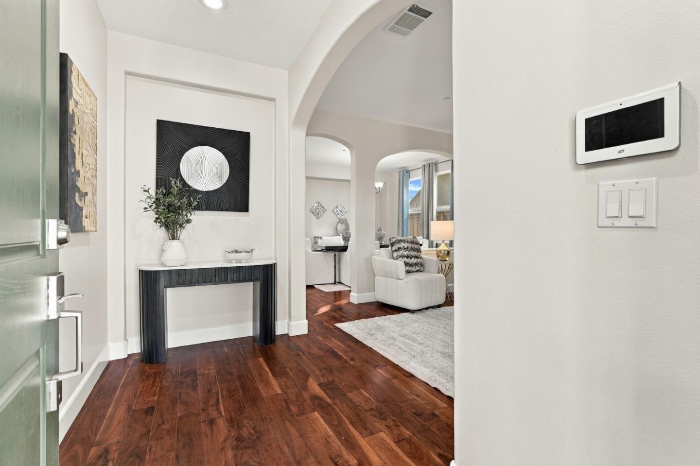 Entry foyer with dark wood floors, black console table, and arched opening to a sitting area.