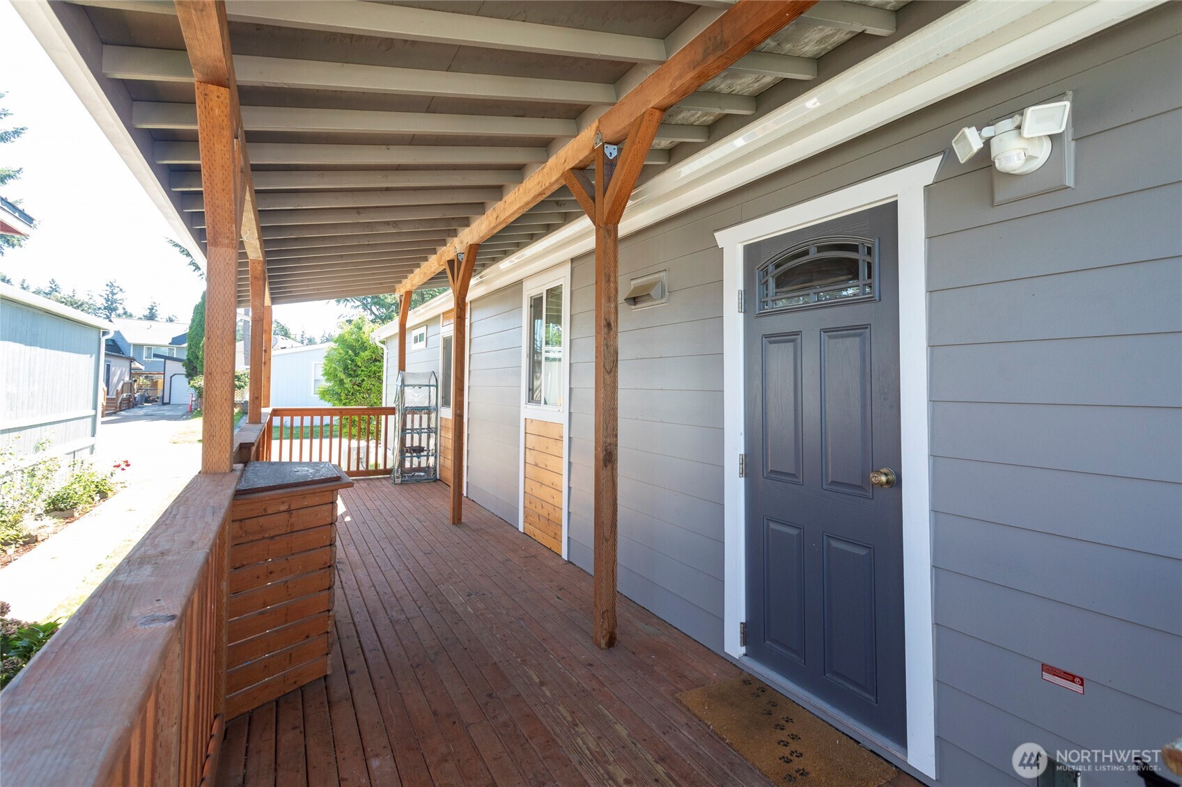 Covered wooden porch with a dark blue front door and built-in bench seating.