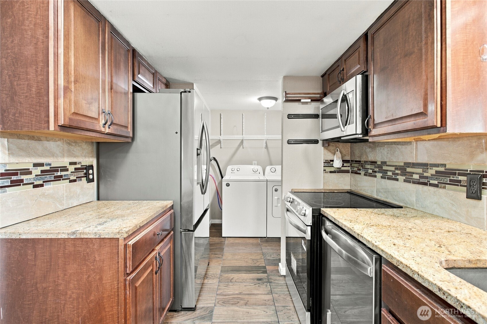 Kitchen with stainless steel appliances, dark wood cabinets, and a laundry area at the back.