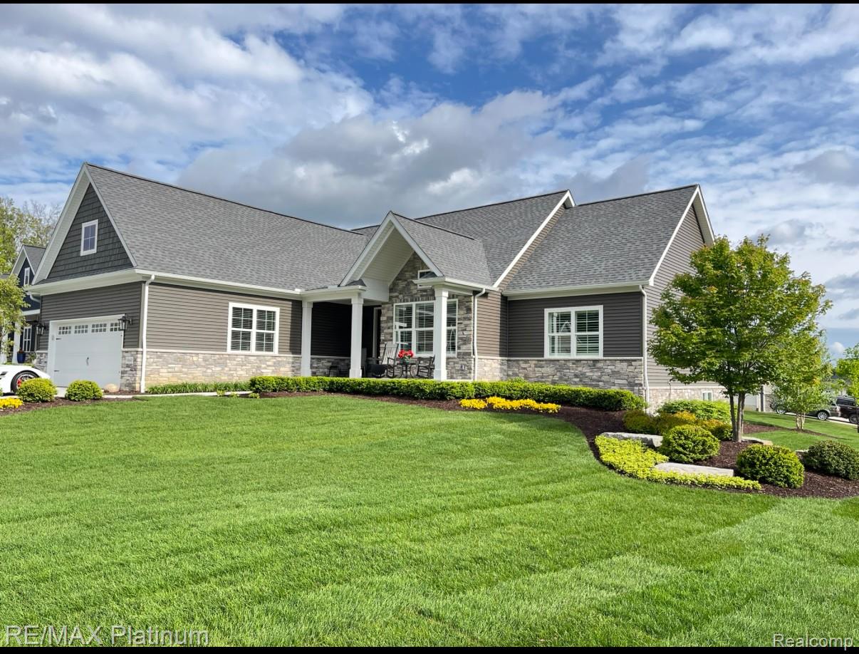 Gray single-story home with stone accents, attached garage, and landscaped front lawn.