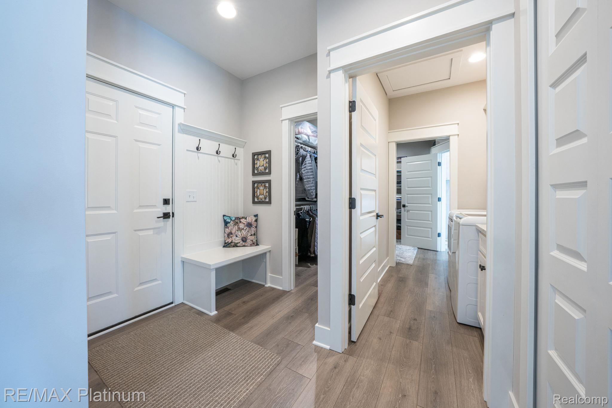 Mudroom with a built-in bench and coat hooks beside an open doorway to the laundry room.