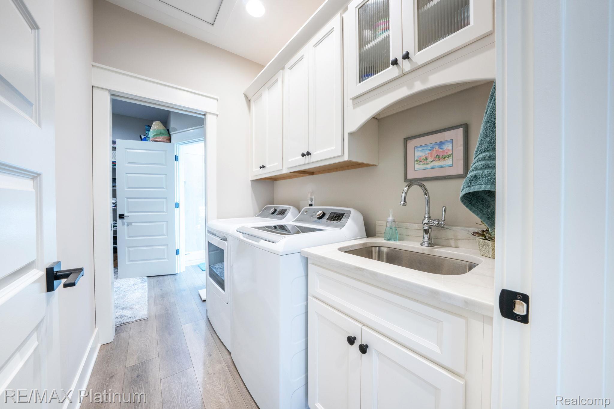 Laundry room with white cabinetry, washer and dryer, and a deep utility sink.