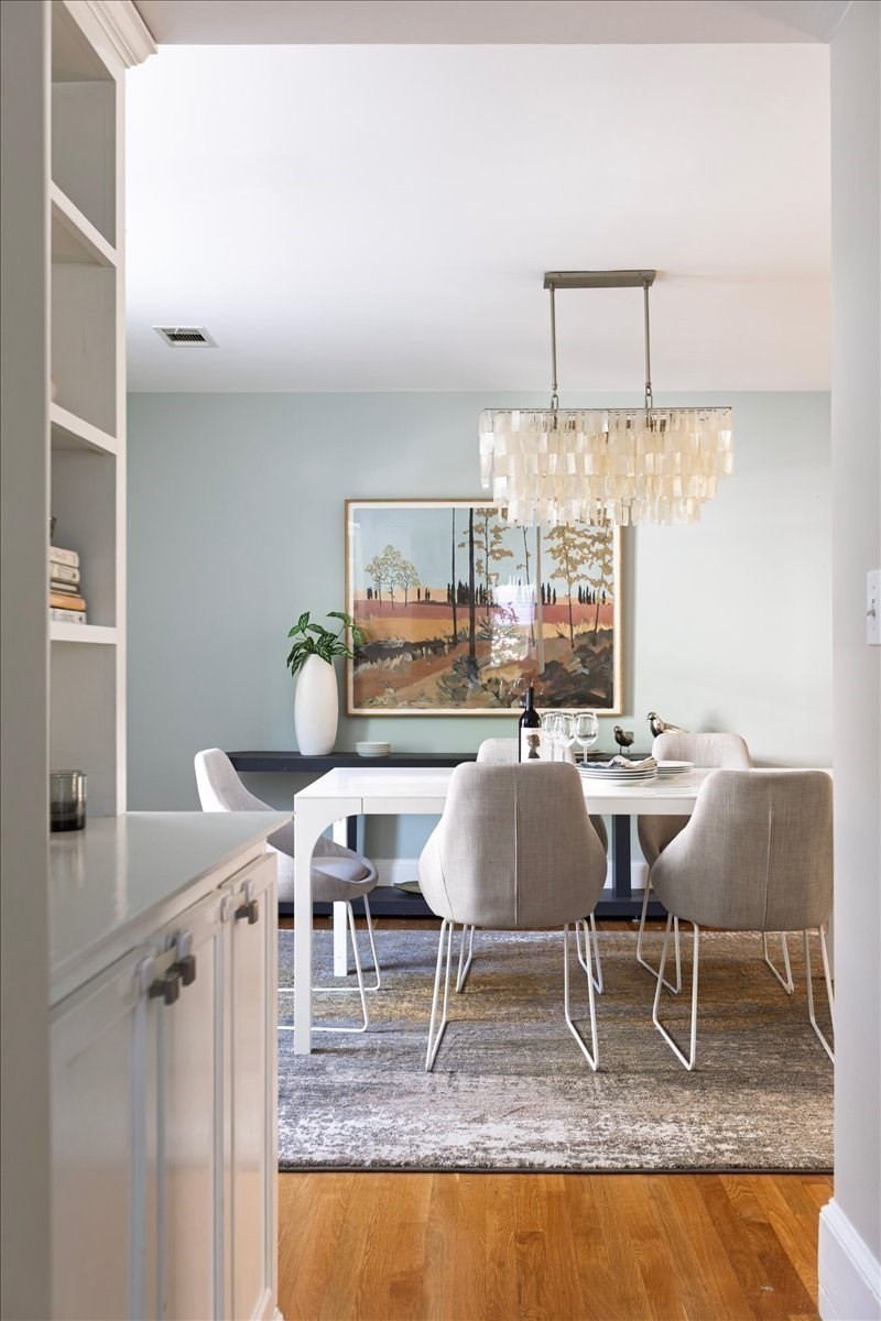 Dining room with a white table, upholstered chairs, and a statement chandelier.