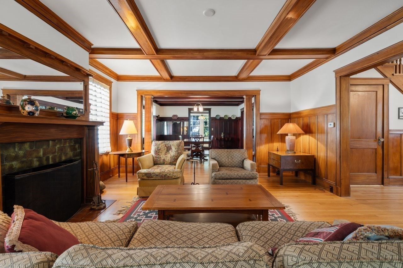 Living room with a large fireplace, wood coffered ceiling, and patterned seating.