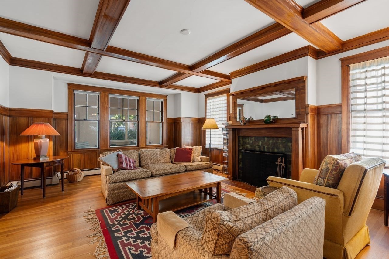 Living room with a coffered wood ceiling, paneled walls, and a large fireplace.