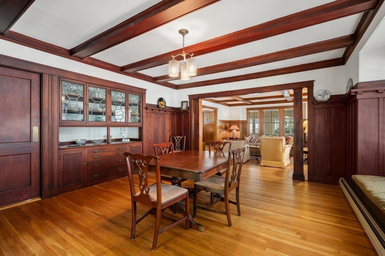 Dining room with dark wood built-ins, a coffered ceiling, and a large wooden table.