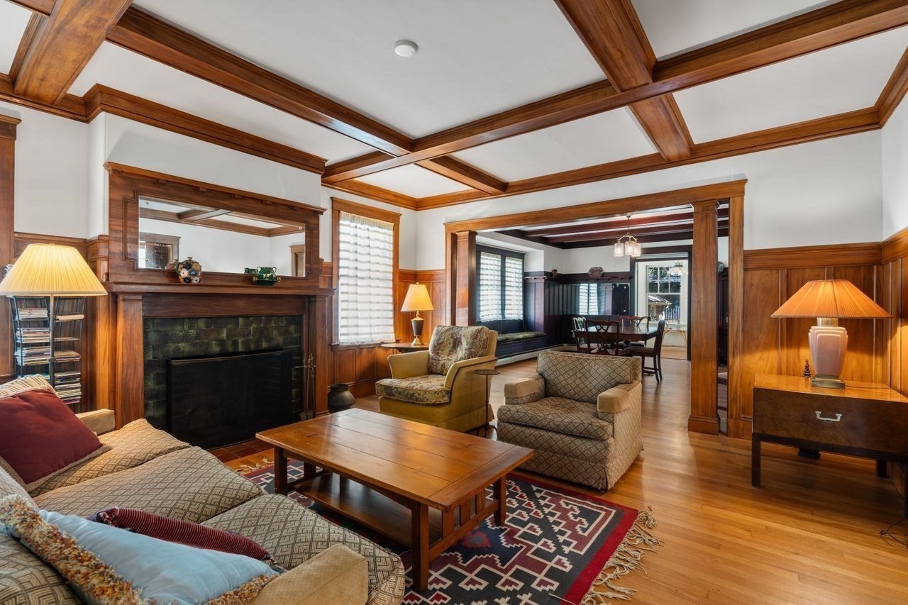 Living room with a coffered wood ceiling, paneled fireplace, and adjoining dining room.