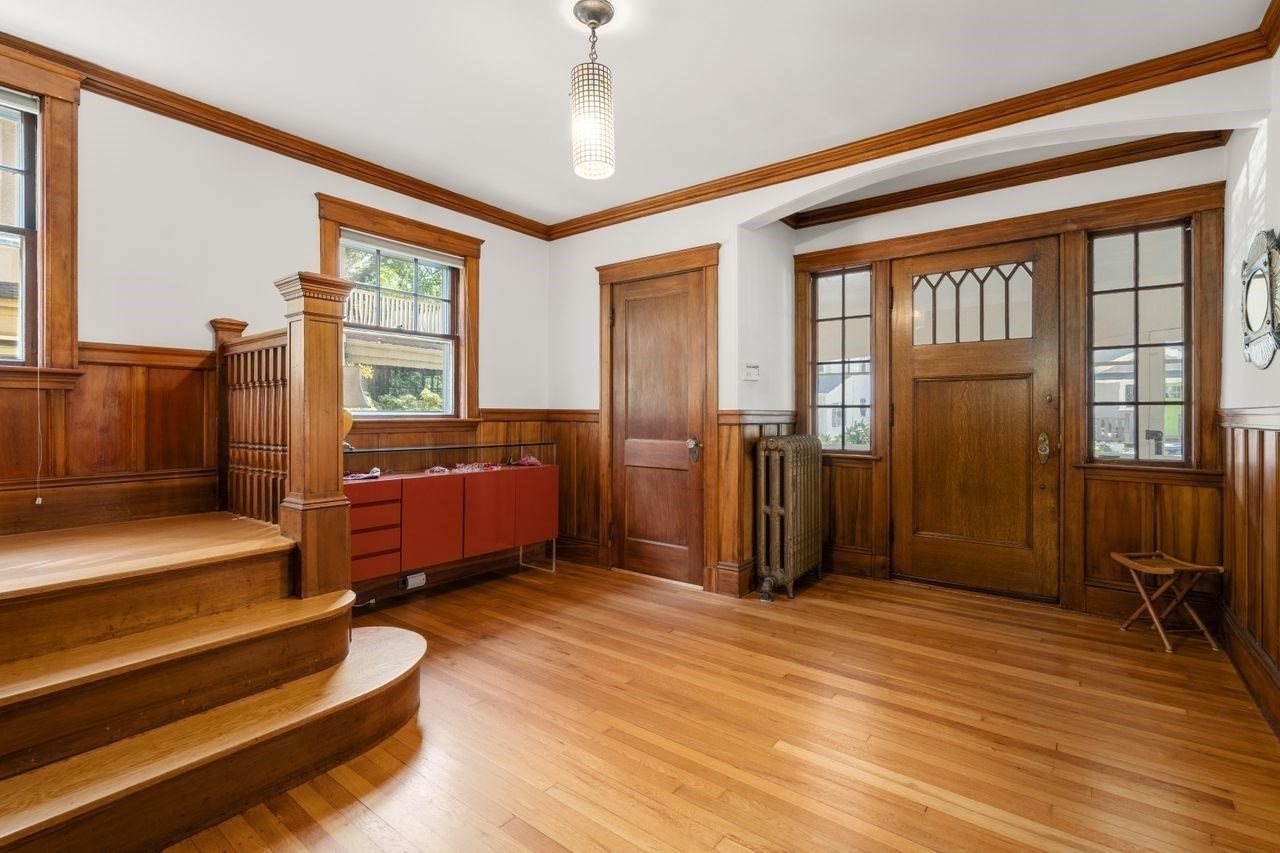 Entry foyer with a curved staircase, rich woodwork, and a front door with decorative glass.