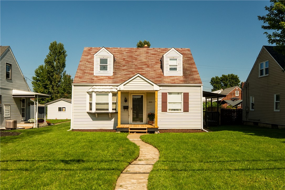 House with a reddish shingle roof, two dormers, bay window, and curved front walkway.