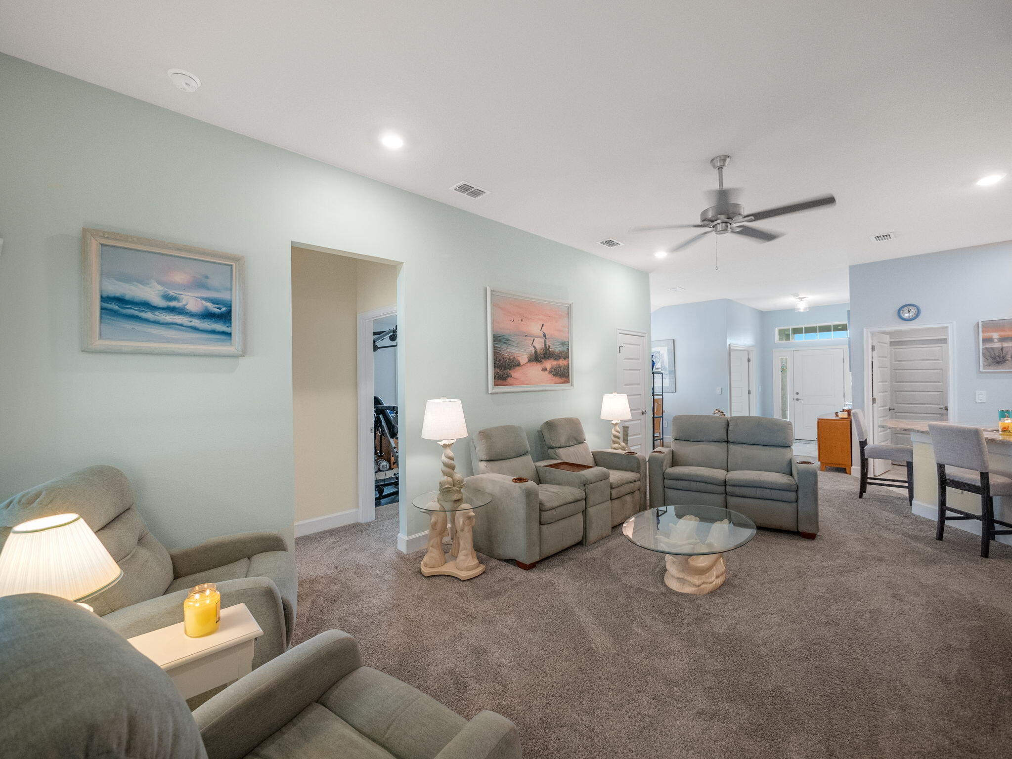Living room with gray reclining furniture, a glass coffee table, and carpeted floors.
