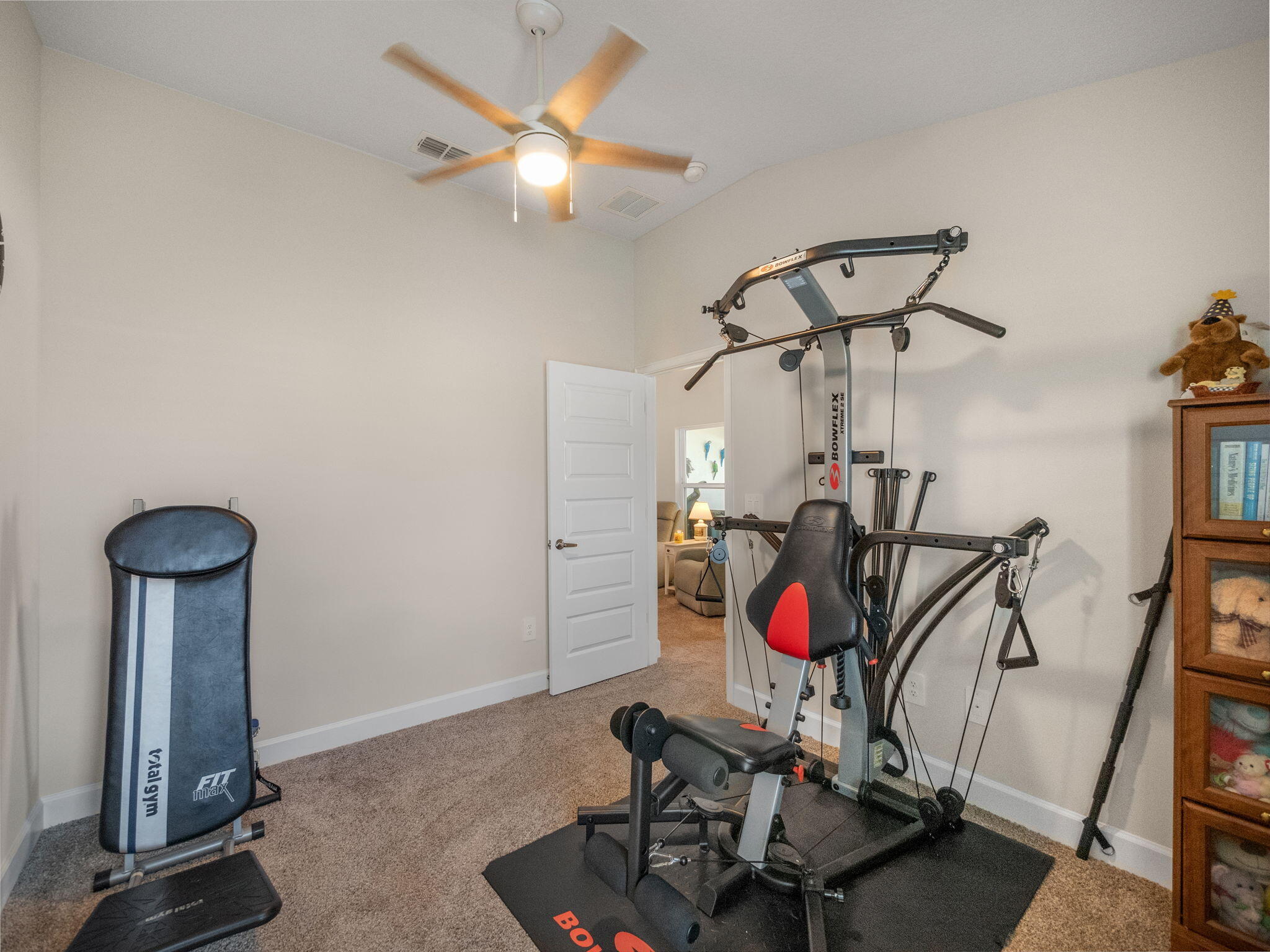 Home gym with a Bowflex workout machine, punching bag, and open doorway.