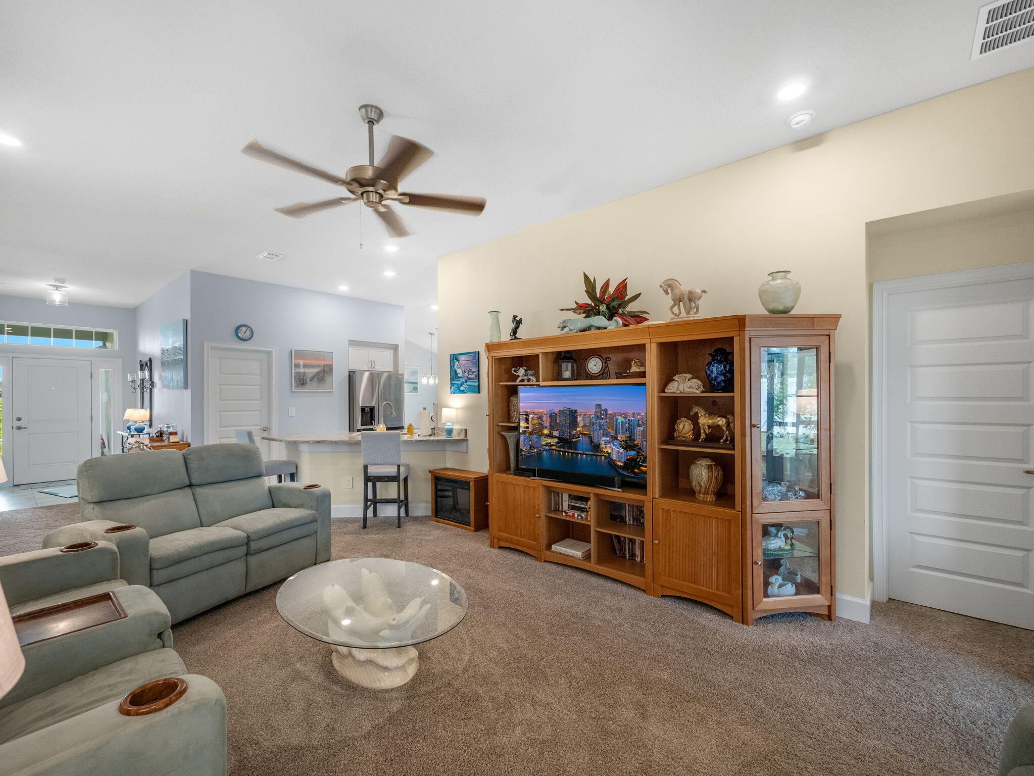 Living room with gray reclining sofas, a glass coffee table, and a wooden entertainment center.