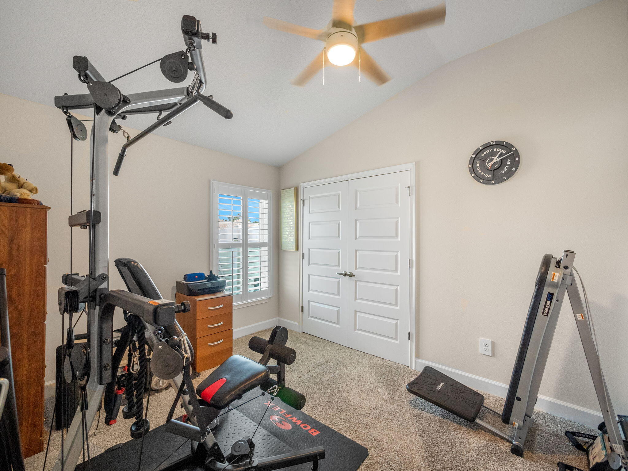 Home gym with Bowflex strength equipment, a separate exercise machine, and white double closet doors.