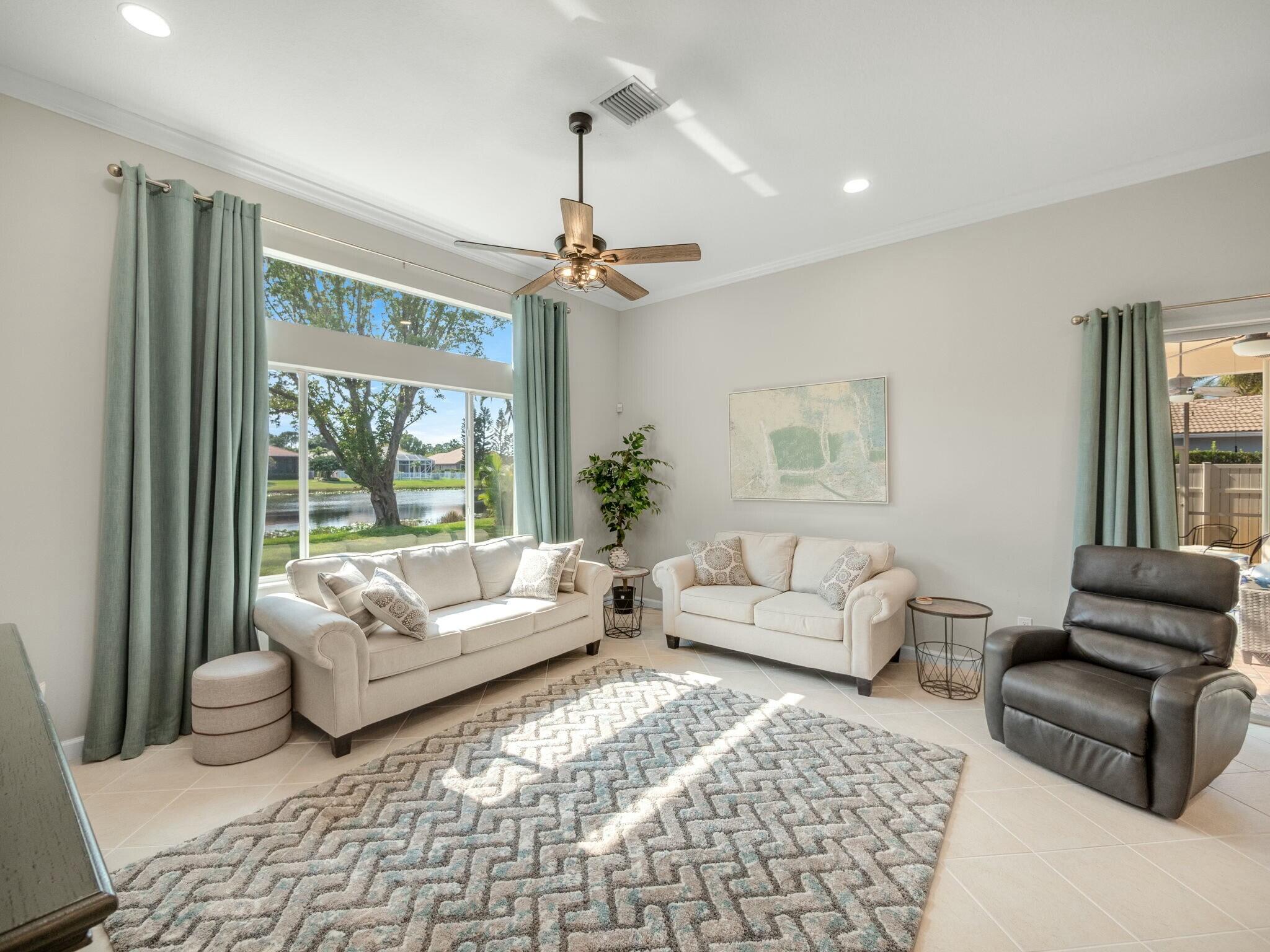 Living room with cream sofas and a leather recliner beside a large canal-view window.