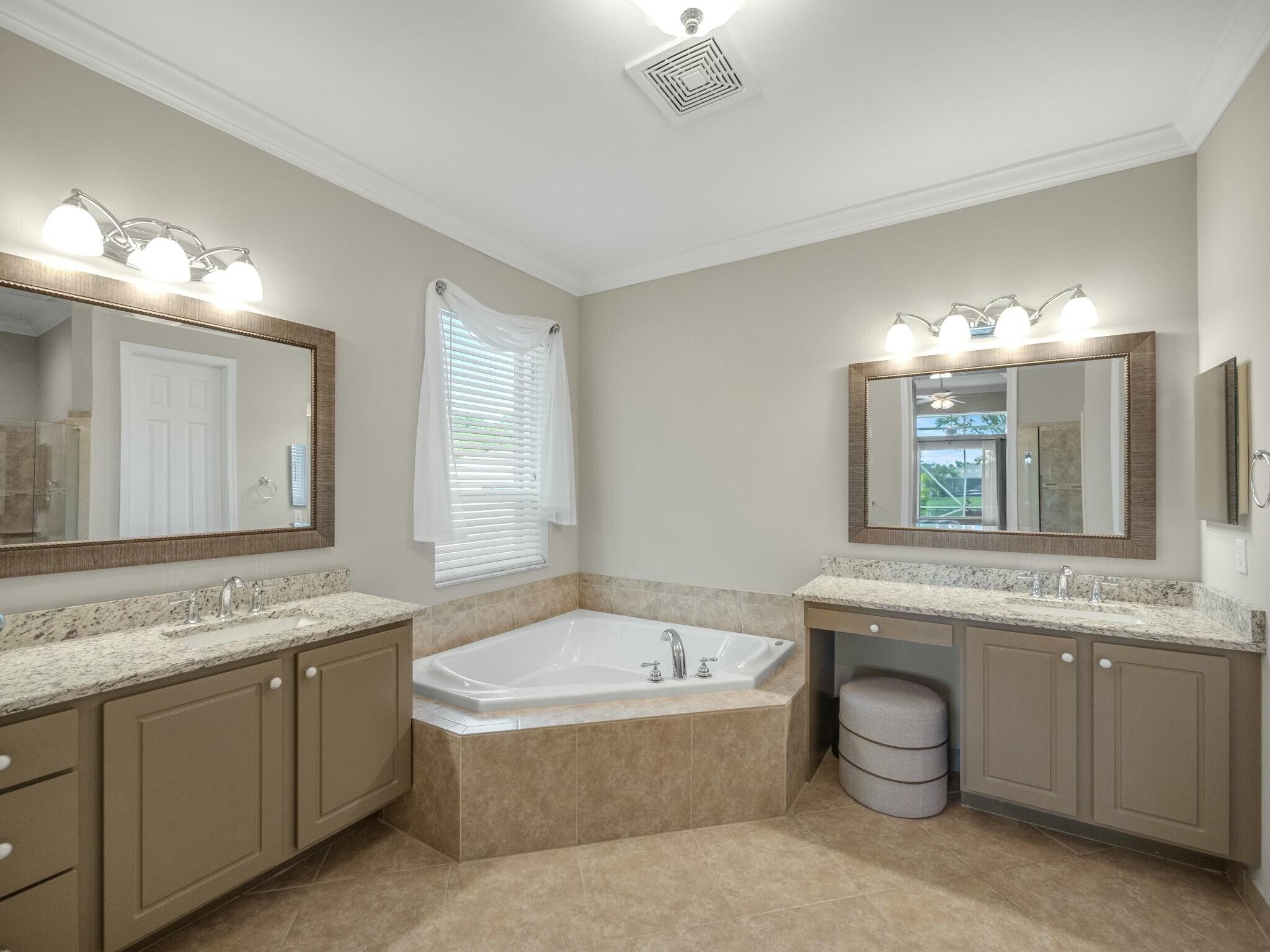 Bathroom with a corner soaking tub and two granite-topped vanities.