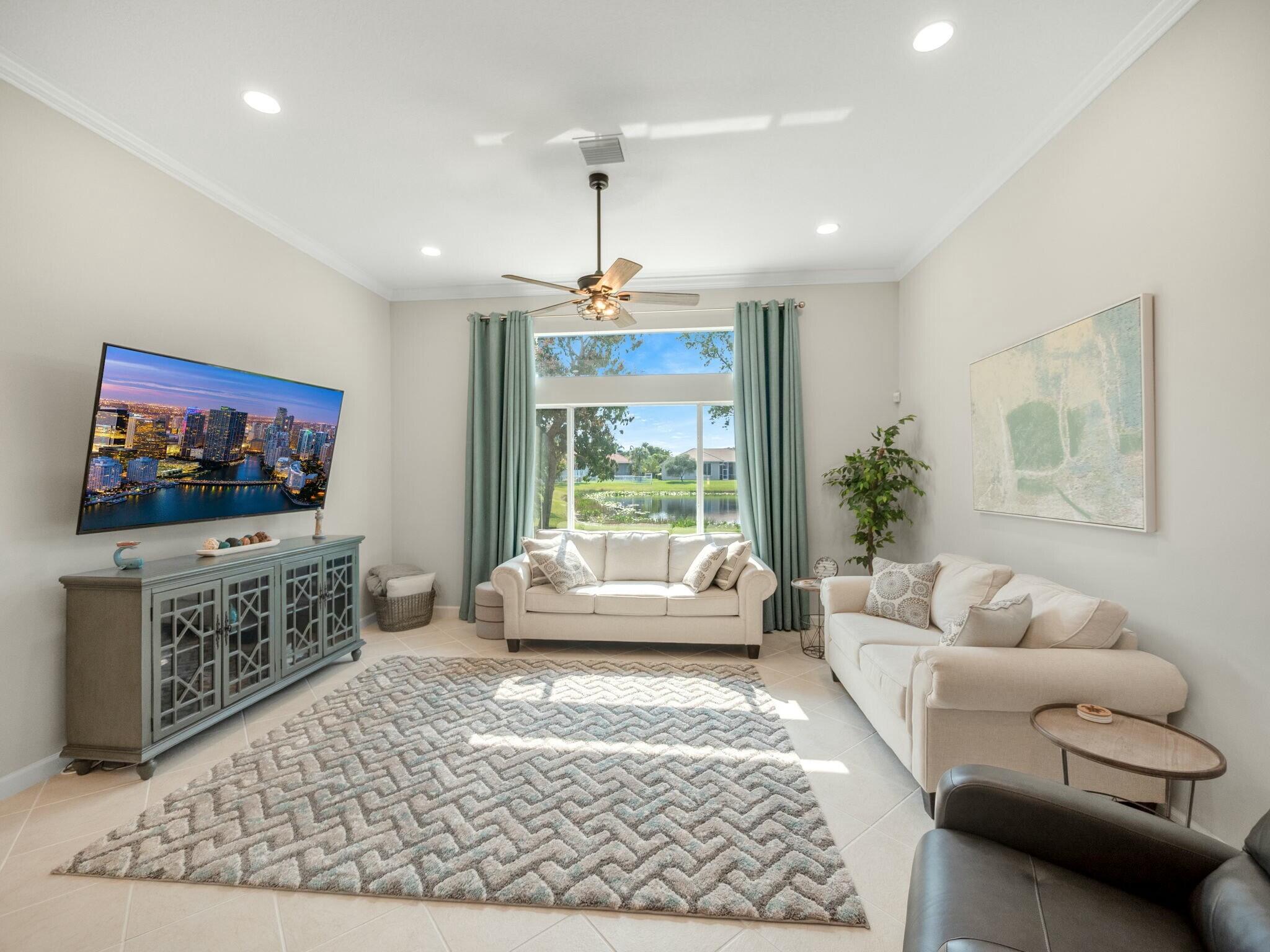 Furnished living room with cream sofas and a large window overlooking a pond.