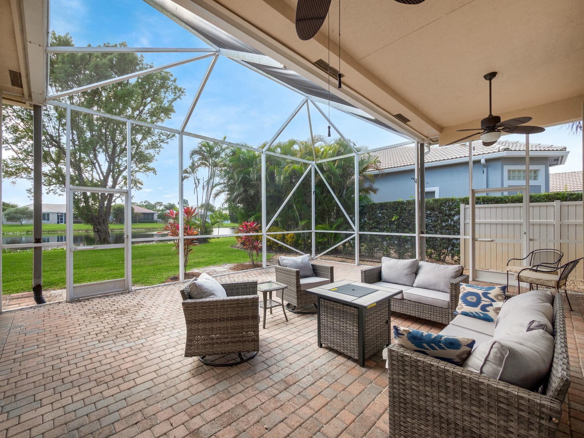 Screened patio with wicker seating and brick pavers overlooking the water.