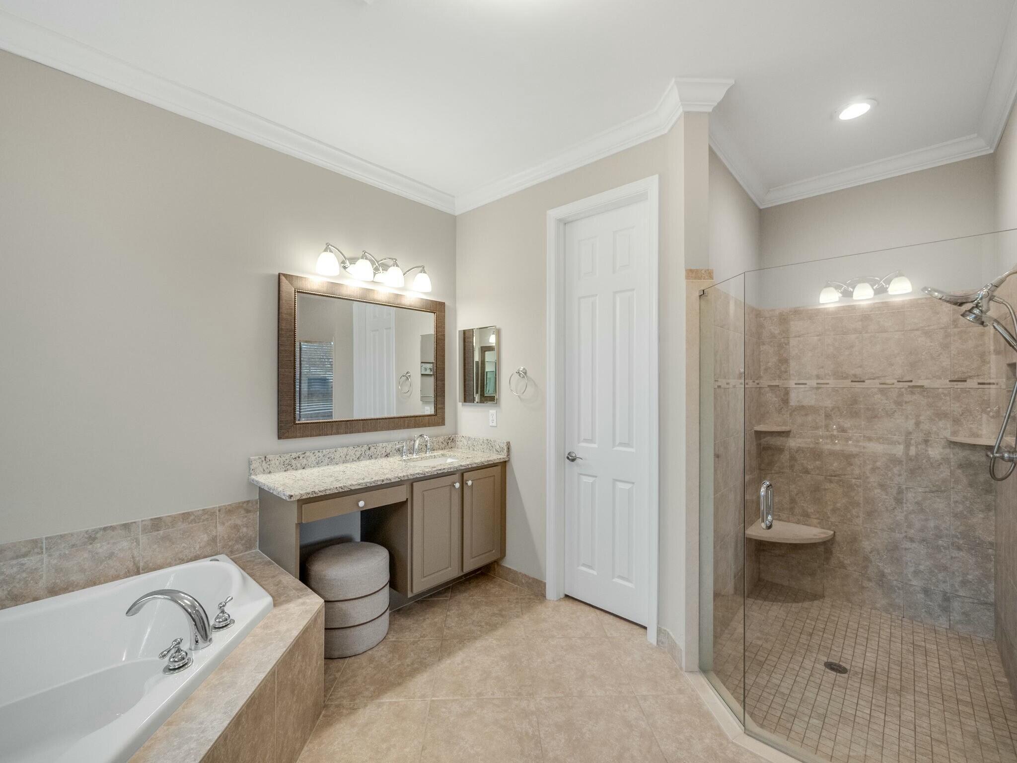 Bathroom with a built-in soaking tub, granite vanity, and glass-enclosed tiled shower.