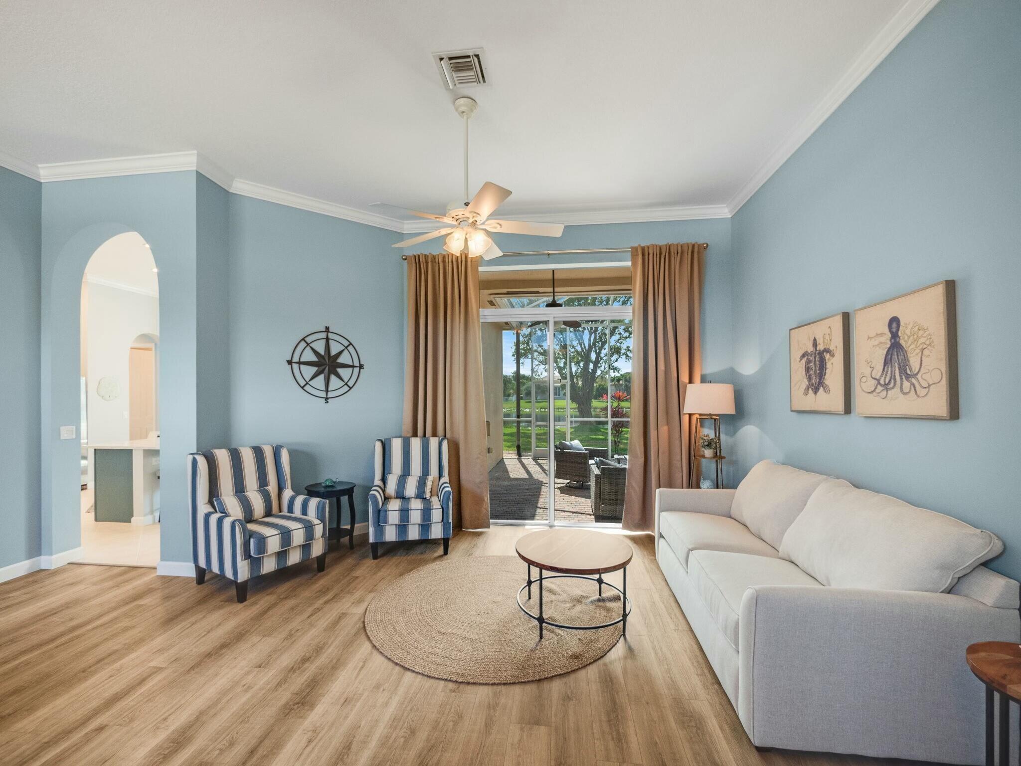 Living room with blue walls, striped armchairs, a white sofa, and sliding doors to a patio.