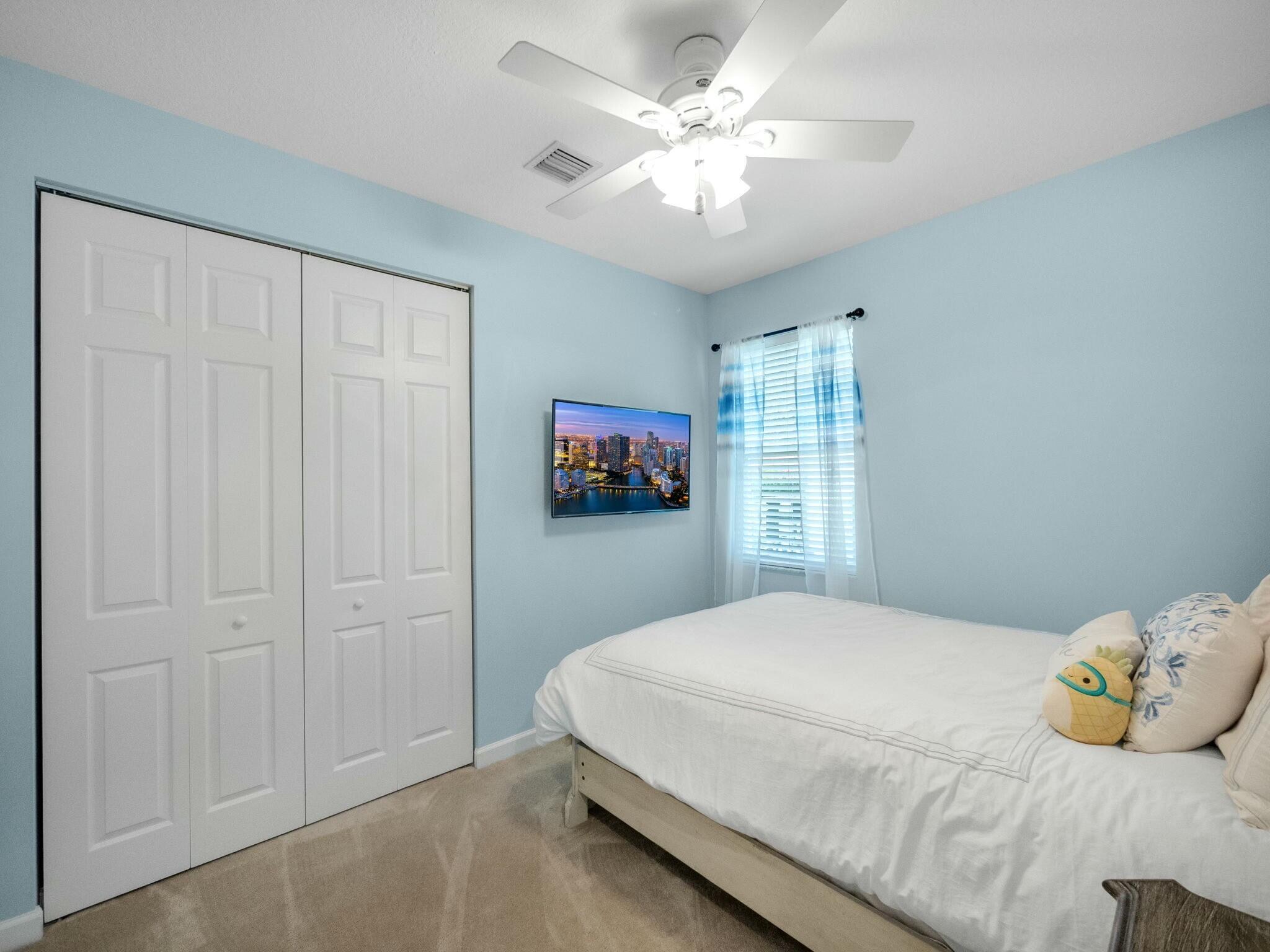 Bedroom with a white bed, sliding closet doors, and light blue walls.