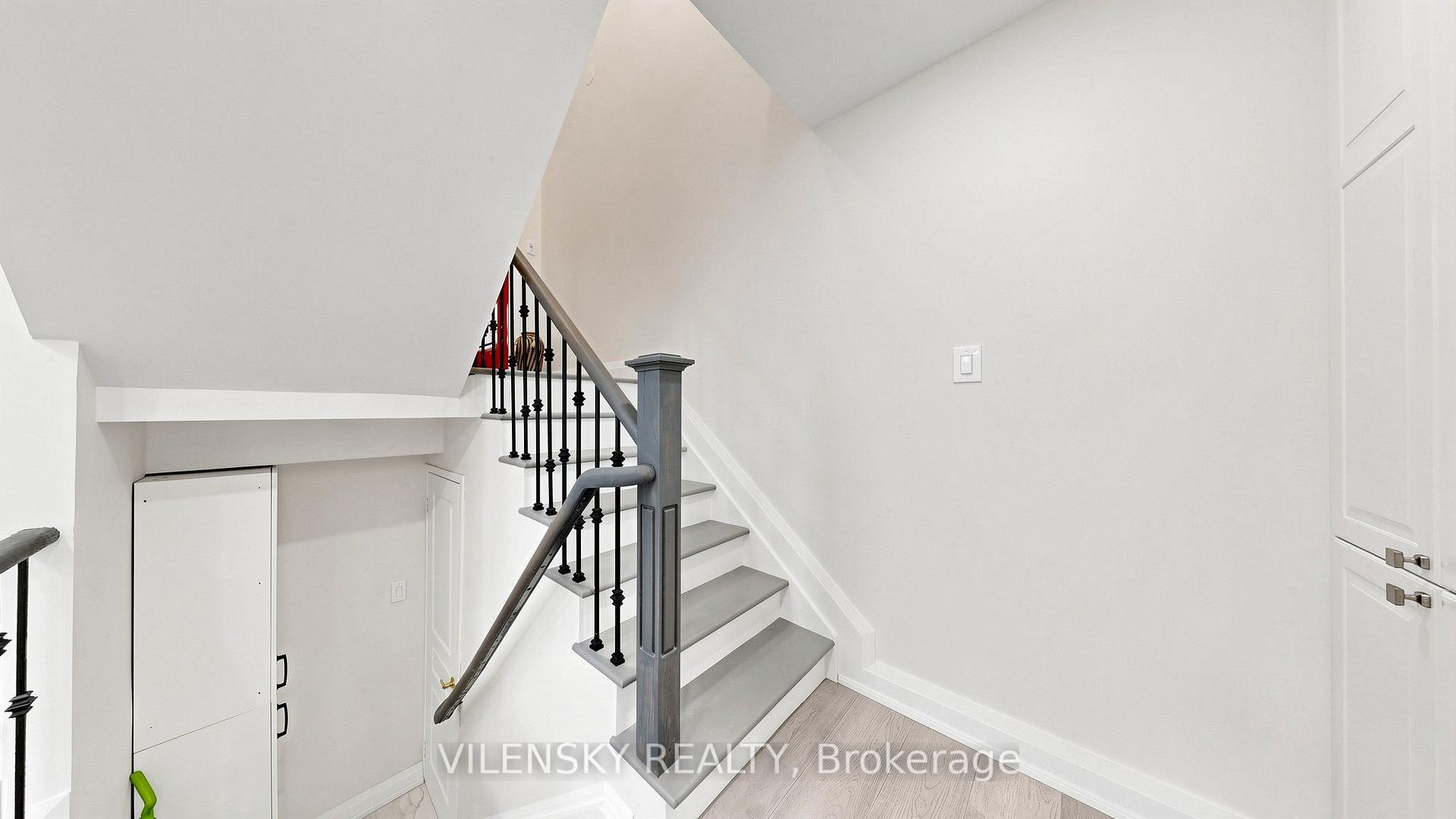 Staircase with gray treads and black iron balusters beside built-in under-stair storage.
