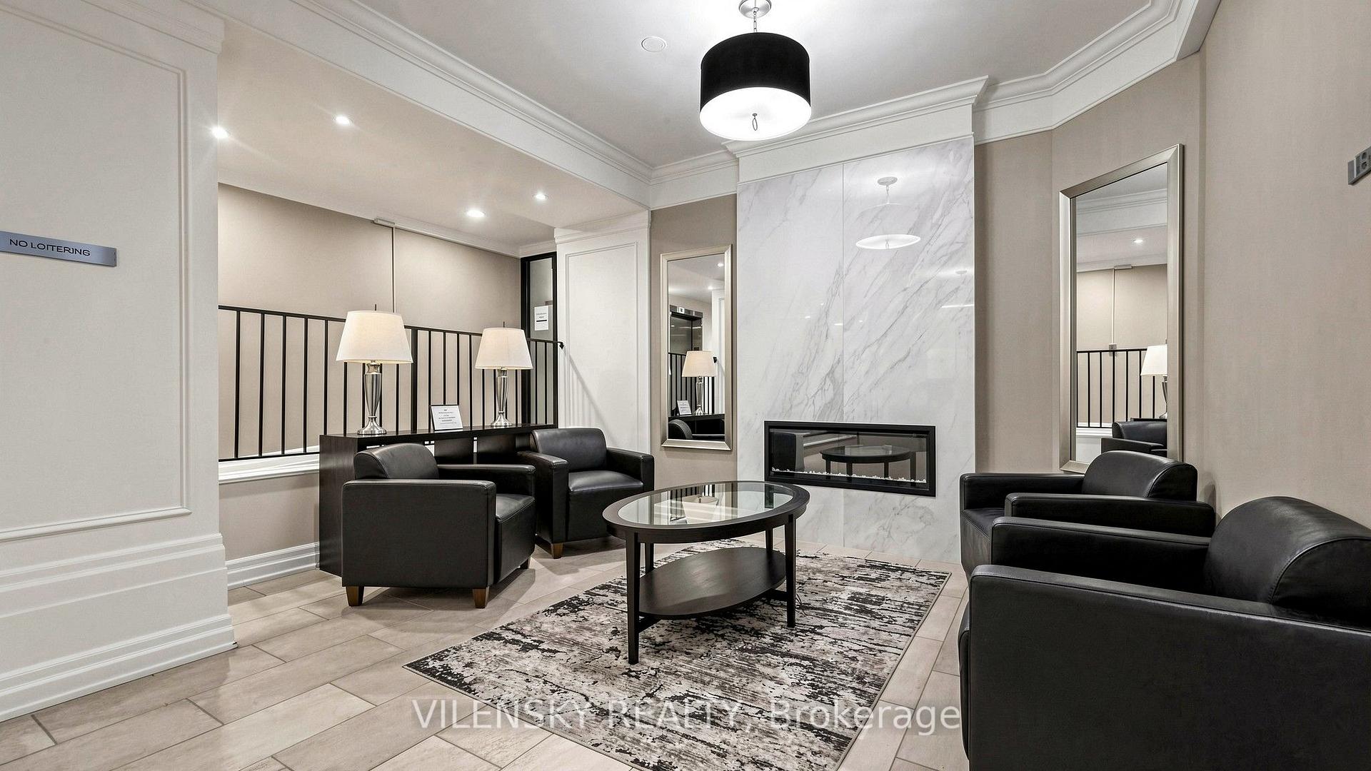 Condominium lounge with leather armchairs, oval glass table, and a marble-look fireplace wall.