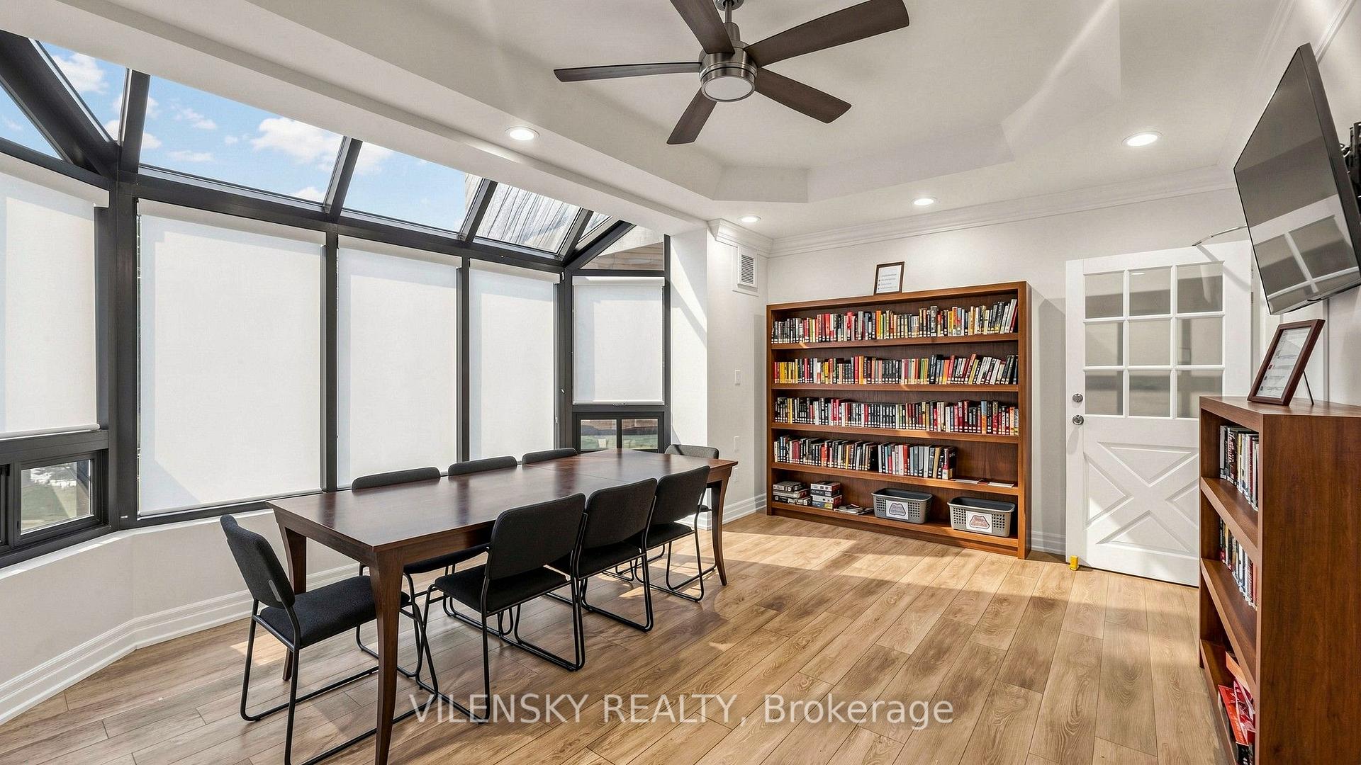 Furnished library meeting room with a conference table, bookshelves, and large slanted windows.