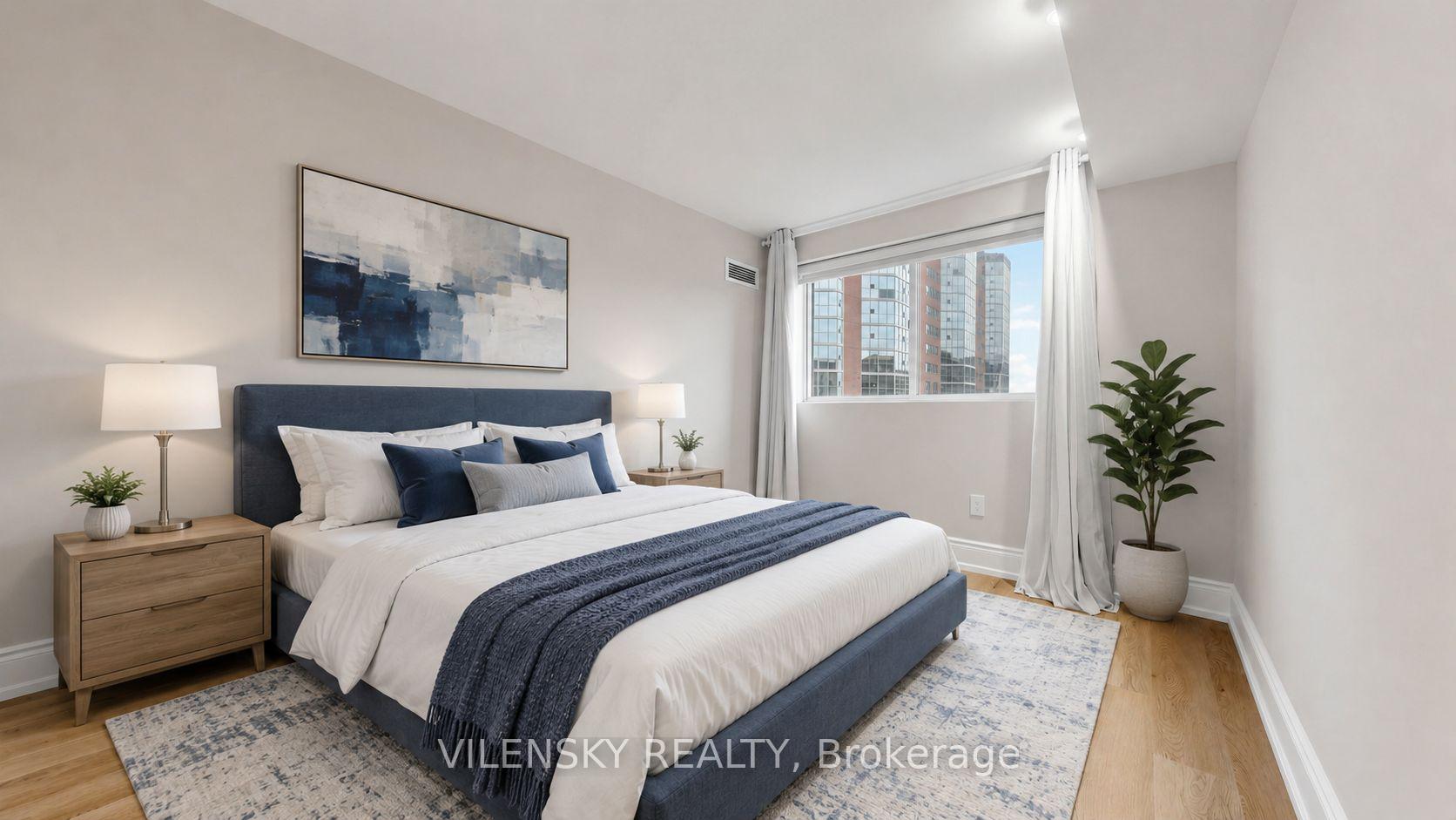 Staged condo bedroom with navy-and-white bedding and a window overlooking high-rise buildings.
