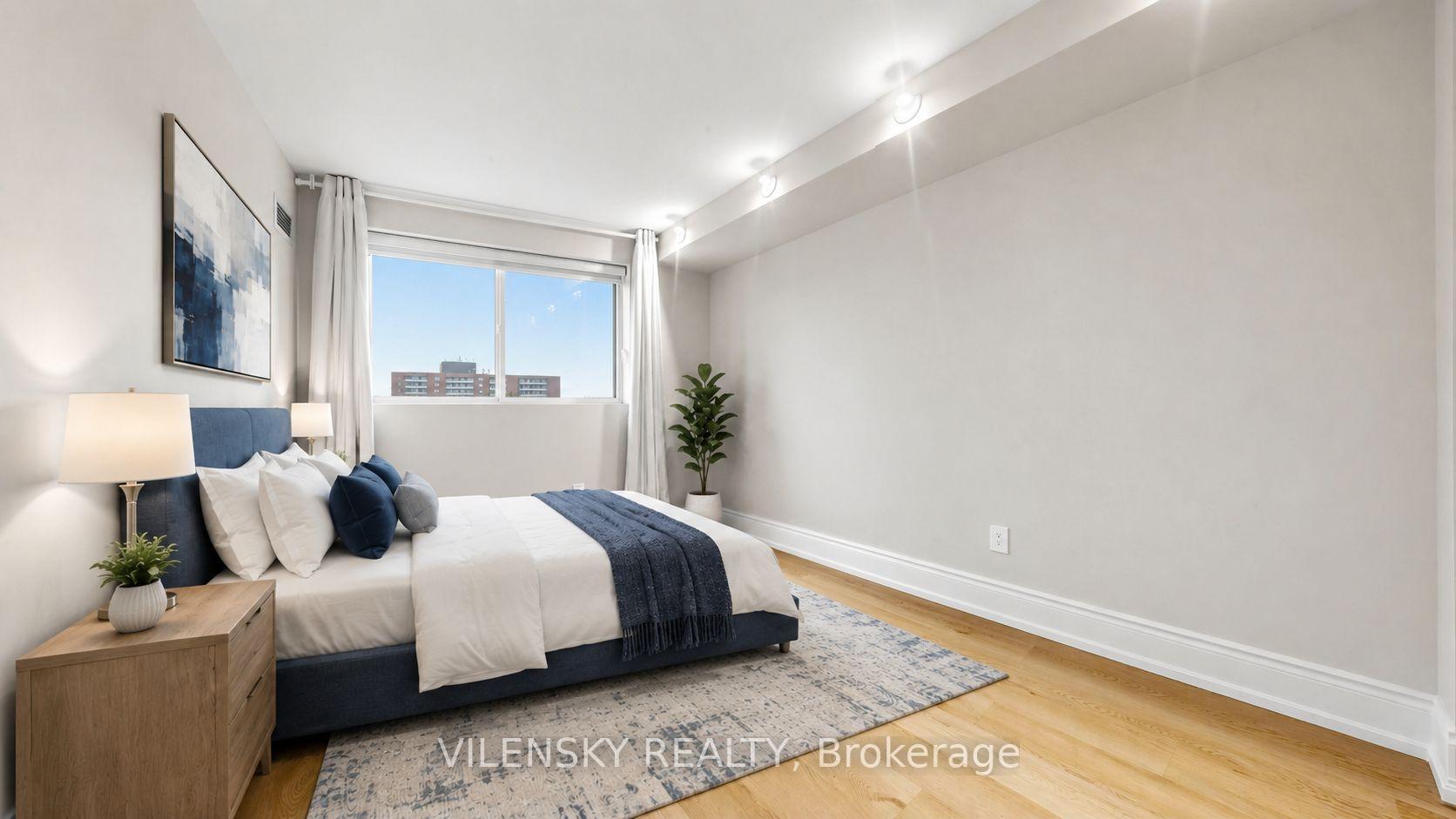Staged bedroom with a blue upholstered bed, white bedding, and a large window.