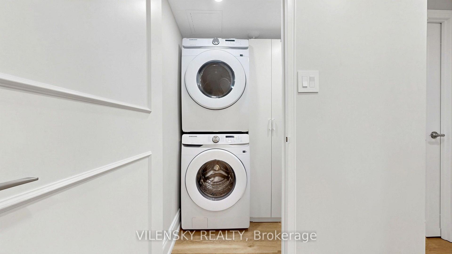 Laundry closet with stacked white washer and dryer beside built-in cabinetry.