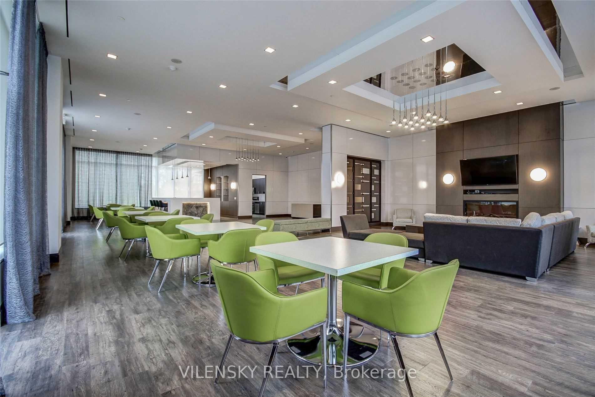 Condominium lounge with green dining chairs, gray sofas, and a fireplace wall.