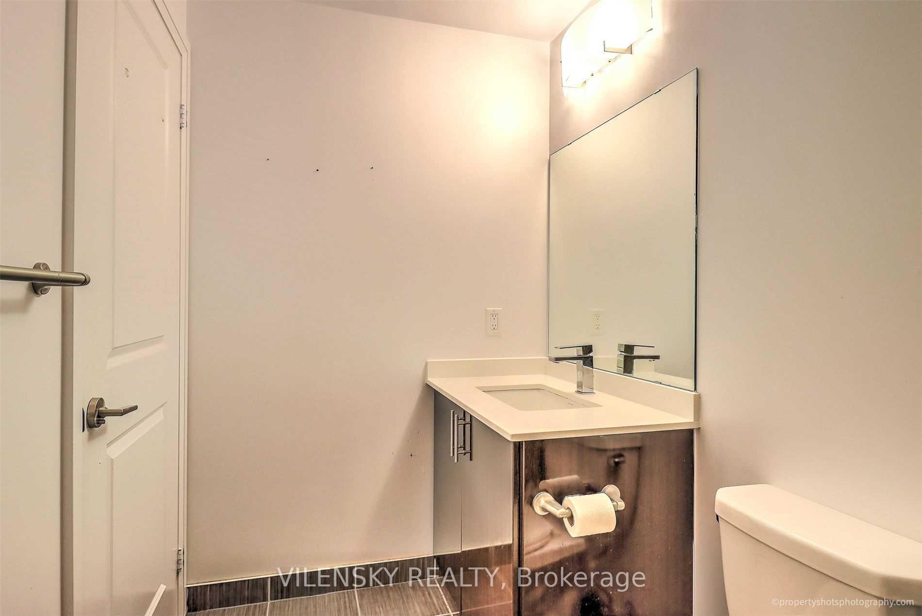 Bathroom vanity with a white sink, dark wood cabinetry, and large wall mirror.