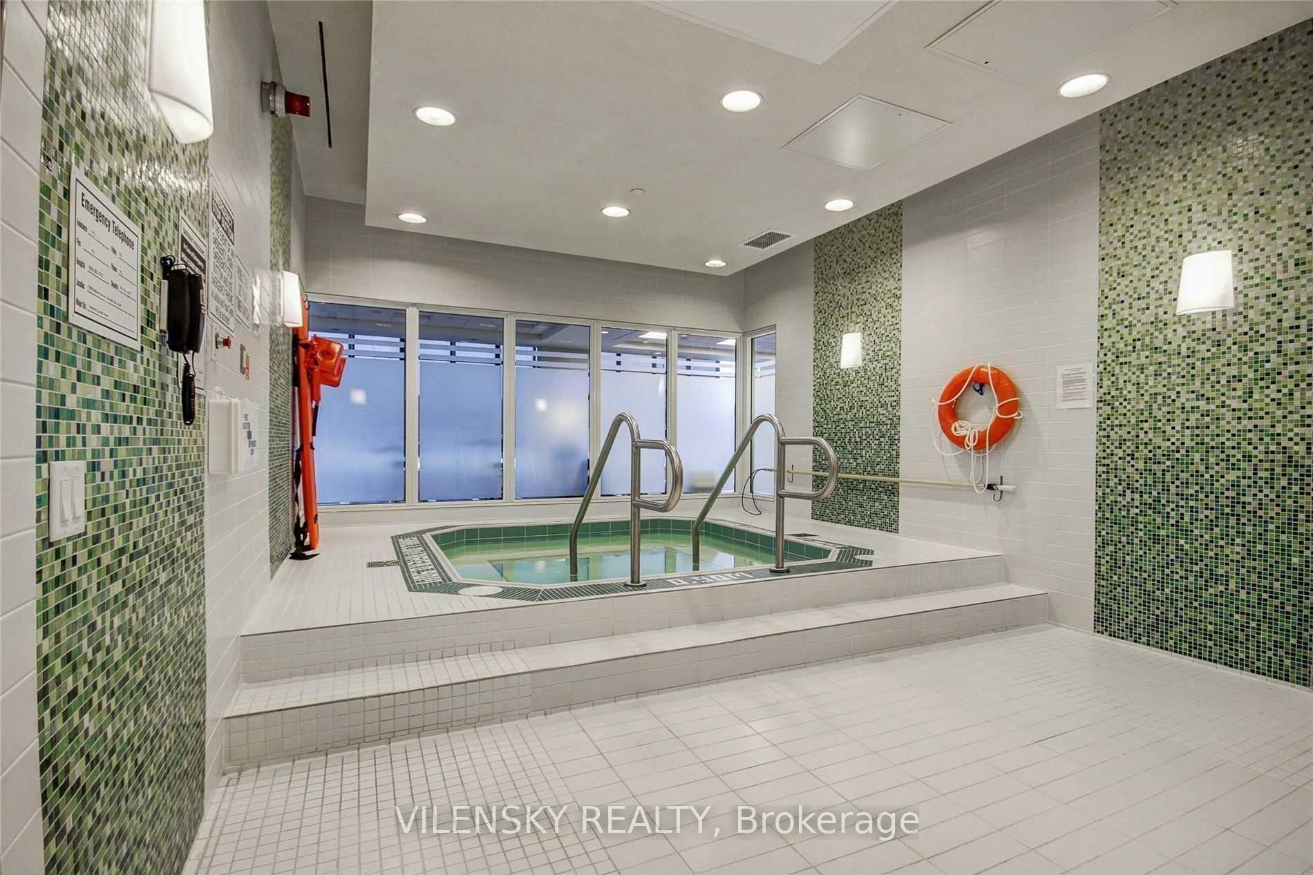 Indoor pool with green mosaic tile, stainless-steel handrails, and a life ring.