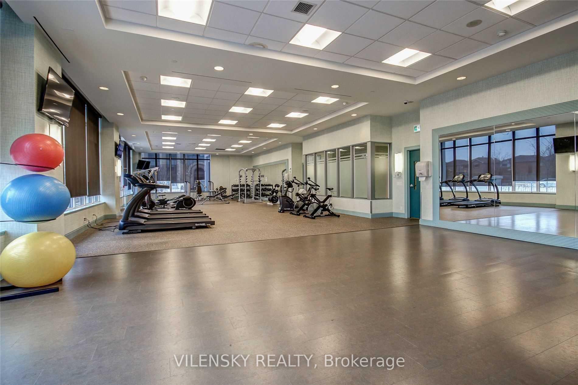 Condominium gym with treadmills, weight equipment, colorful exercise balls, and a mirrored workout area.